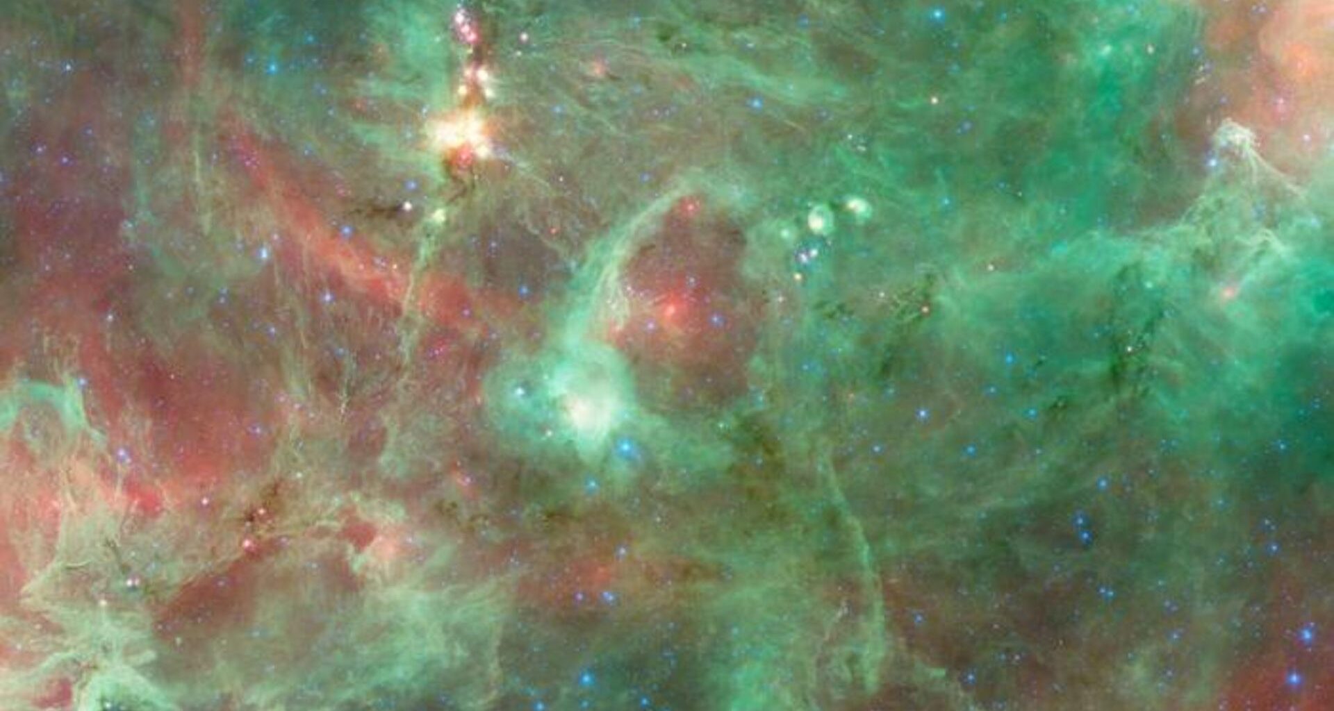 Swirls of green and red gas surrounded a bright white light in the middle of the image