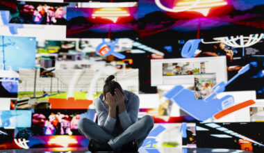 Young man stares at smartphone in distress symbolizing toxic impact of social media on mental health. Likes, posts and endless scrolling lead to stress, anxiety and depression. Overwhelmed user.