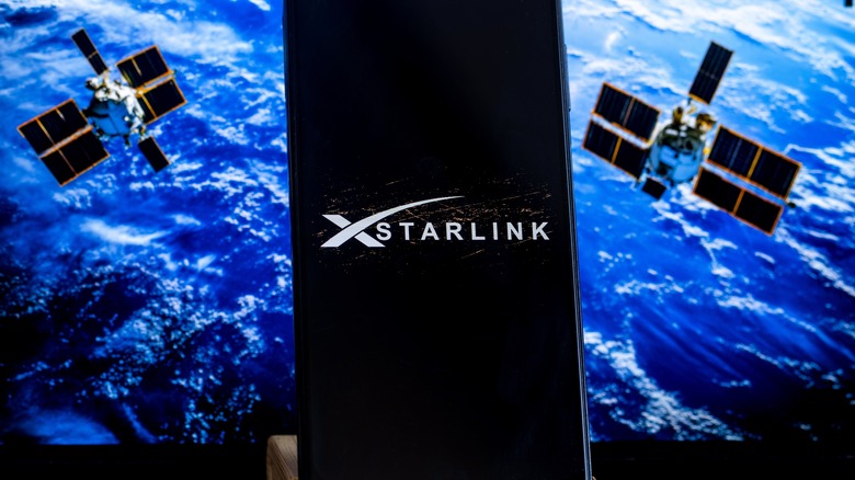 The Starlink logo on a tablet, set against a background of satellites orbiting Earth.