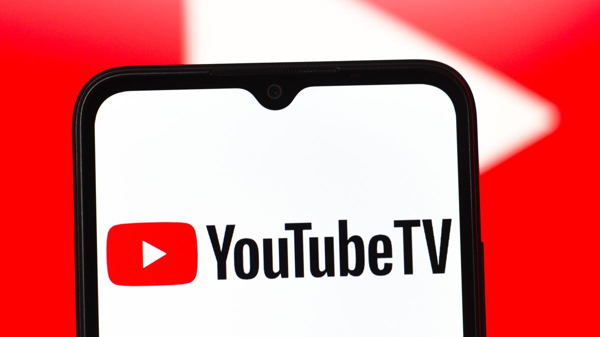 the YouTube TV logo on a mobile phone in front of a large red video play button in the background