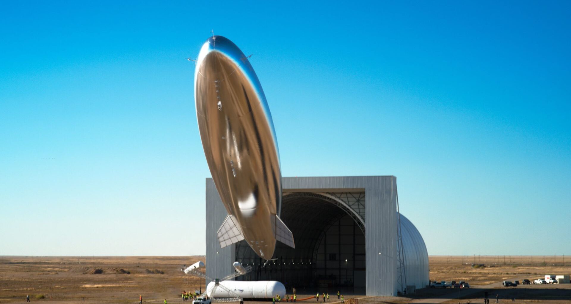 A silvery blimp shape satellite seems to float above the desert of New Mexico