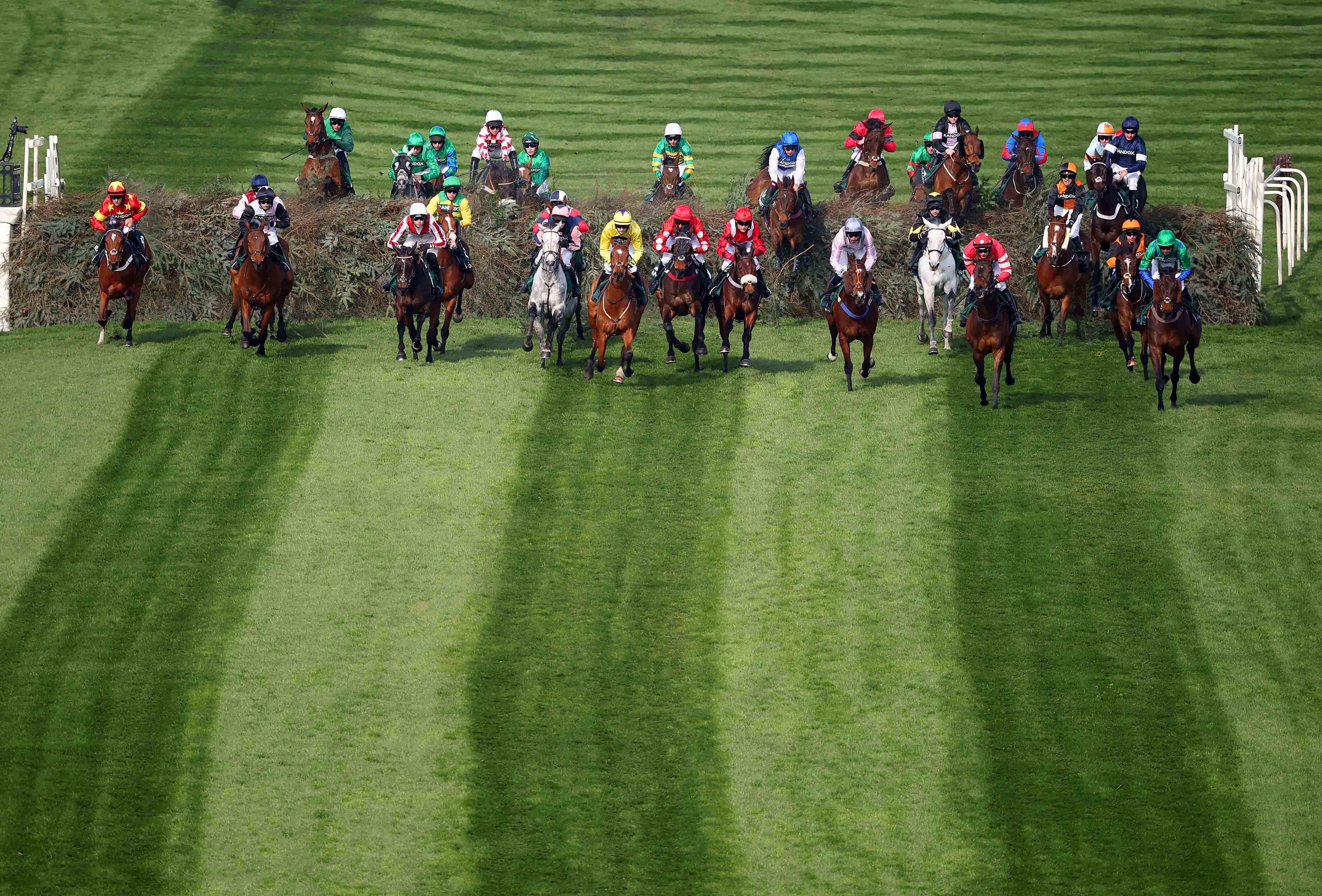 Horses and riders in a race jumping over The Chair at Aintree.