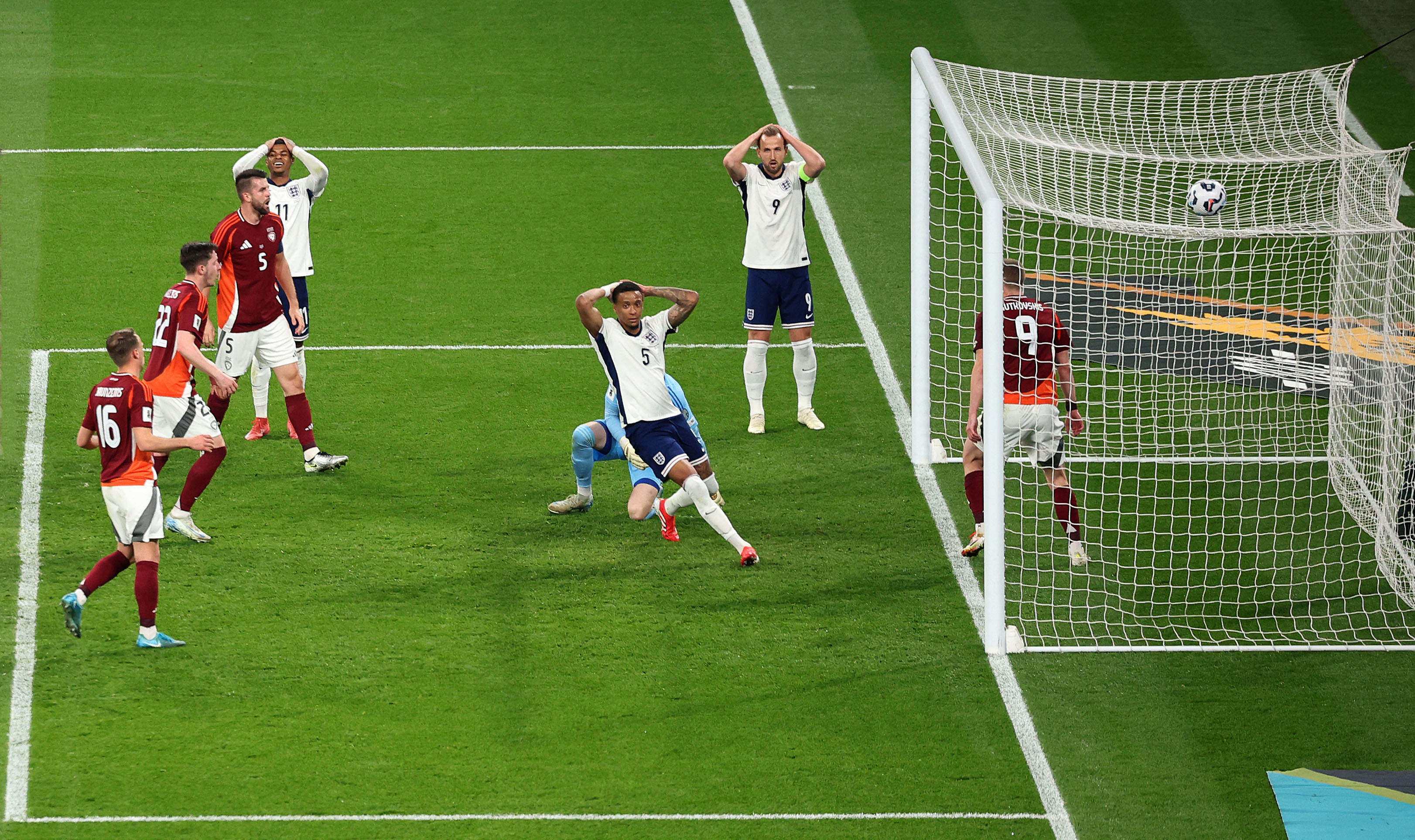 England and Latvia players reacting with hands on heads and a soccer ball in the net during the England v Latvia match at Wembley Stadium.