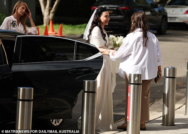 The bride was all smiles as she climbed out of a limousine outside the synagogue