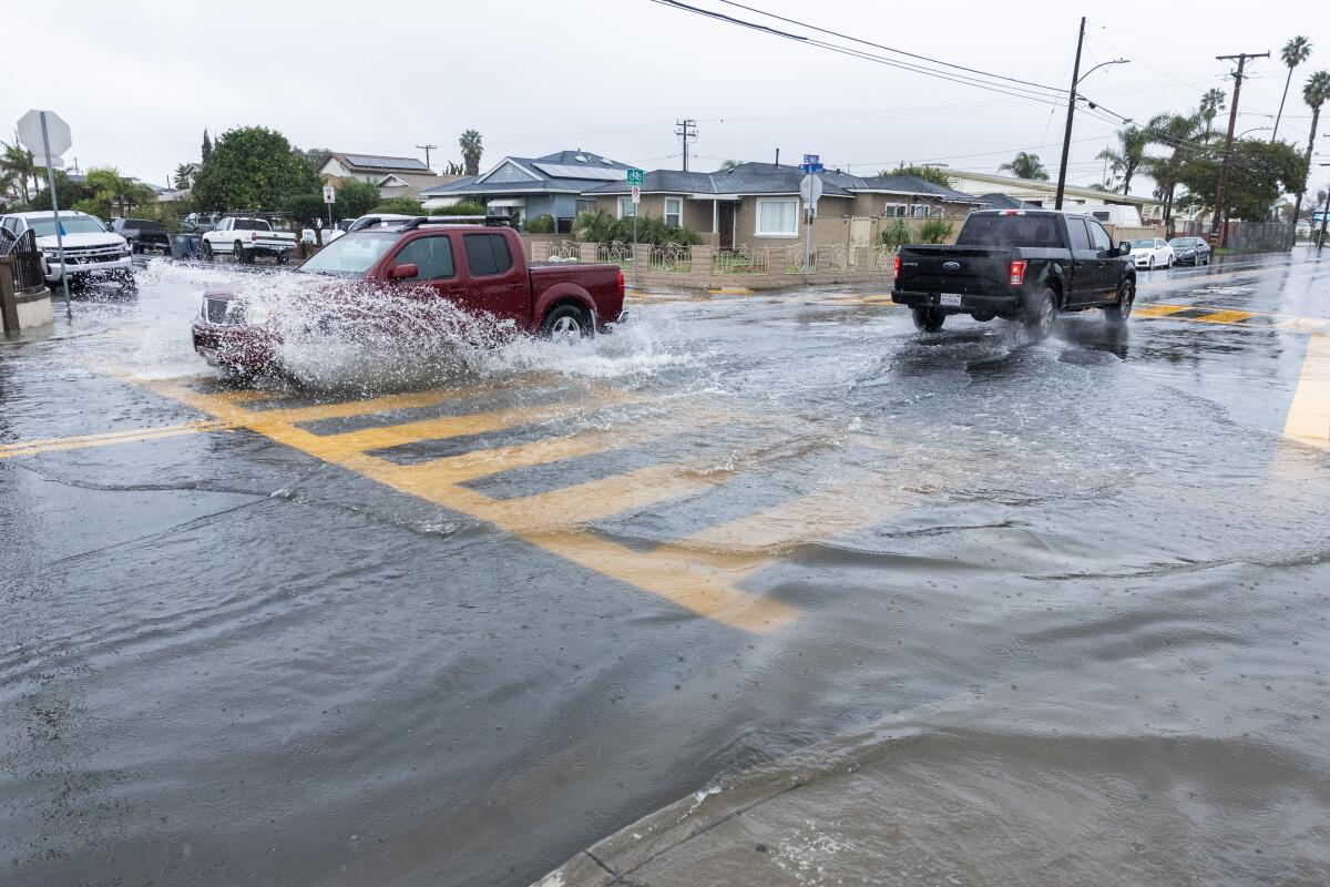 A flooded intersection with vehicles driving through it.