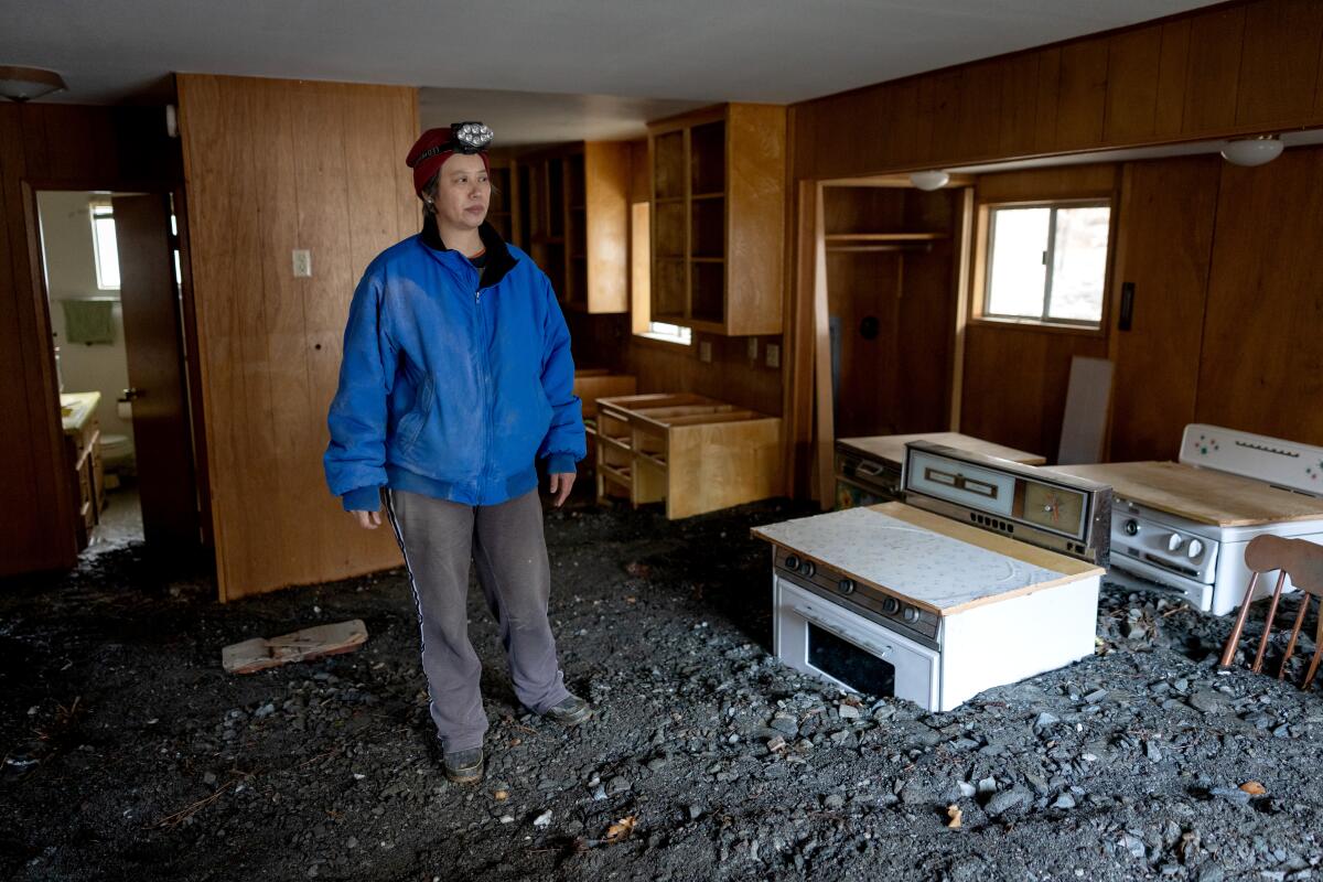 Misty Cheng looks at flood damage to her home in Wrightwood on Thursday.