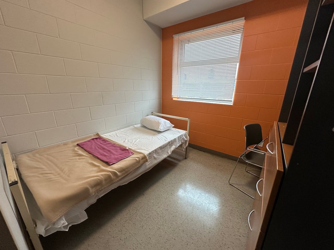 A small single bed inside a concrete room. 