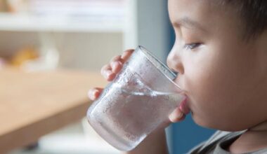 Young boy drinking a glass of water.