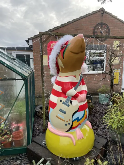 Amber Macey/BBC Standalone image of the striped giant rat sculpture. It is placed on a yellow plinth and has elaborate eye make up