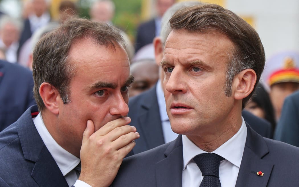 France's President Emmanuel Macron (R) speaks with France's Minister of Armed Forces Sebastien Lecornu (L) after taking part in a wreath-laying ceremony at the monument of national heroes and martyrs in Hanoi on May 26, 2025.