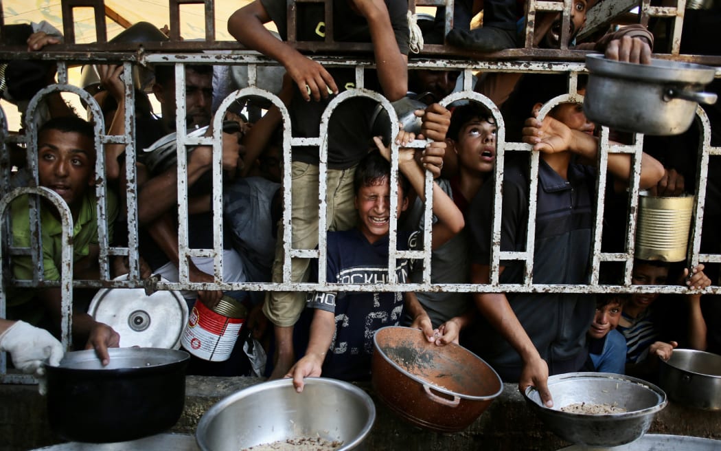 Palestinian children wait for a meal at a charity kitchen in the Mawasi area of Khan Yunis in the southern Gaza Strip on July 22, 2025.