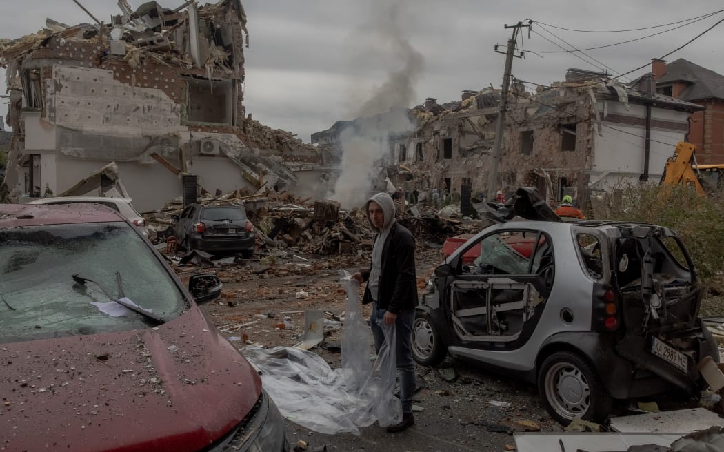 A man prepares to cover a damaged car with a plastic sheet at the site of heavily damaged residential buildings following a Russian air attack on the outskirts of Kyiv, on September 28, 2025, amid the Russian invasion of Ukraine. An overnight Russian barrage on Kyiv killed at least four people, including a 12-year-old girl, Ukrainian authorities said on September 28, 2025.
