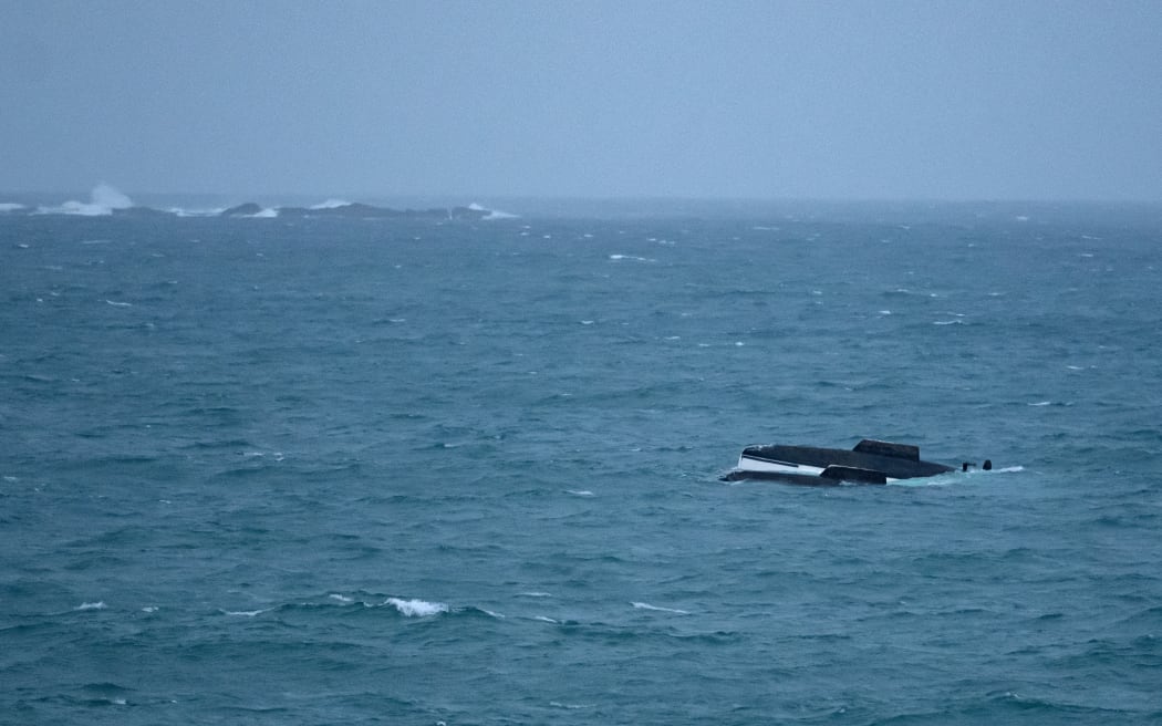 A man was rescued but his dog is still missing after his catamaran struck Elizabeth Reef off Whananaki on Northland's east coast on Tuesday afternoon, December 30 2025. The yacht subsequently capsized and the owner was rescued by a private boatie from Whanaki but his dog, which was wearing a lifejacket has not been found. The damaged catamaran washed up on Sandy Bay surf beach overnight. Photo shows the capsized catamaran drifting towards Sandy Bay at dusk on Tuesday evening. Photo Malcolm Pullman