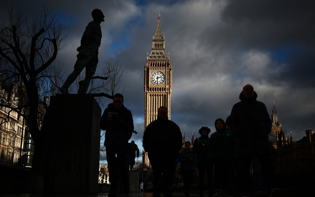 Pedestrians walk past the Elizabeth Tower, commonly known by the name of the clock's bell "Big Ben", at the Palace of Westminster, home to the Houses of Parliament, in central London, at sunset, on January 6, 2025. (Photo by HENRY NICHOLLS / AFP)
