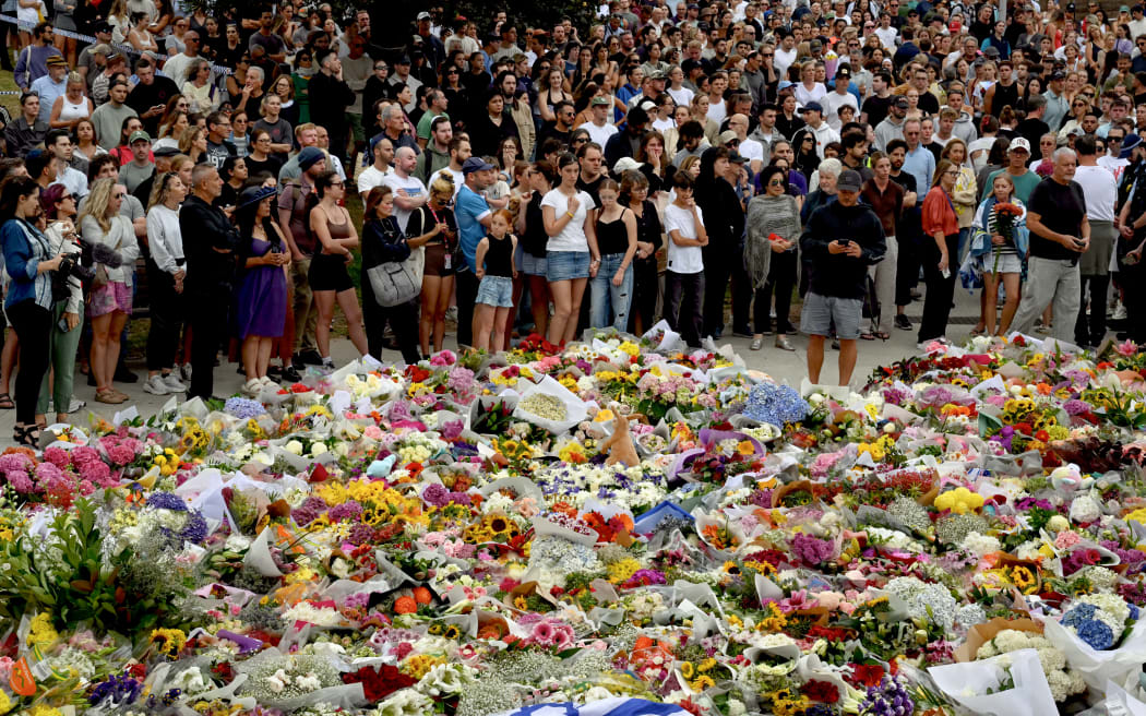 Mourners gather by floral tributes at the Bondi Pavillion in memory of the victims of a shooting at Bondi Beach, in Sydney on December 15, 2025. A father and son opened fire on a Jewish festival at Australia's Bondi Beach in a shooting spree that killed 15 people, including a child, authorities said on December 15, denouncing the attack as antisemitic "terrorism". (Photo by Saeed KHAN / AFP)