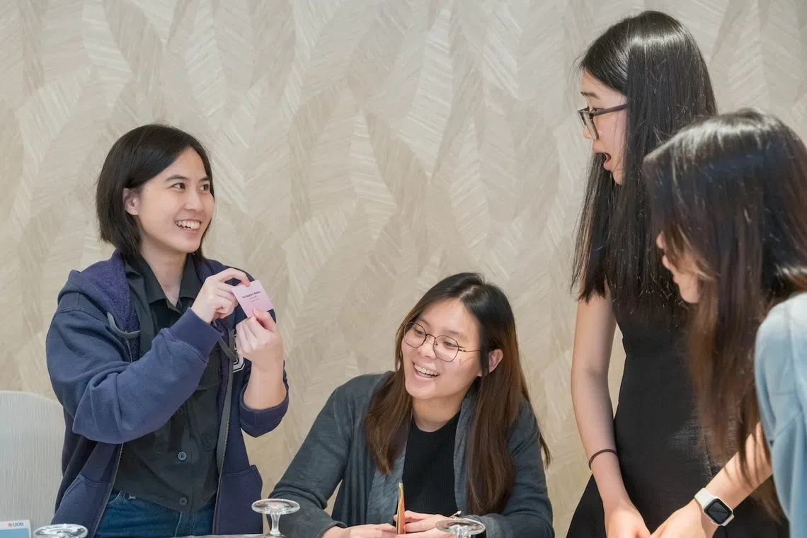 At a workshop organised by UOB in July, Ms Sarah Chee (second from left) learnt financial concepts, such as the importance of insurance and building passive income, through a board game.