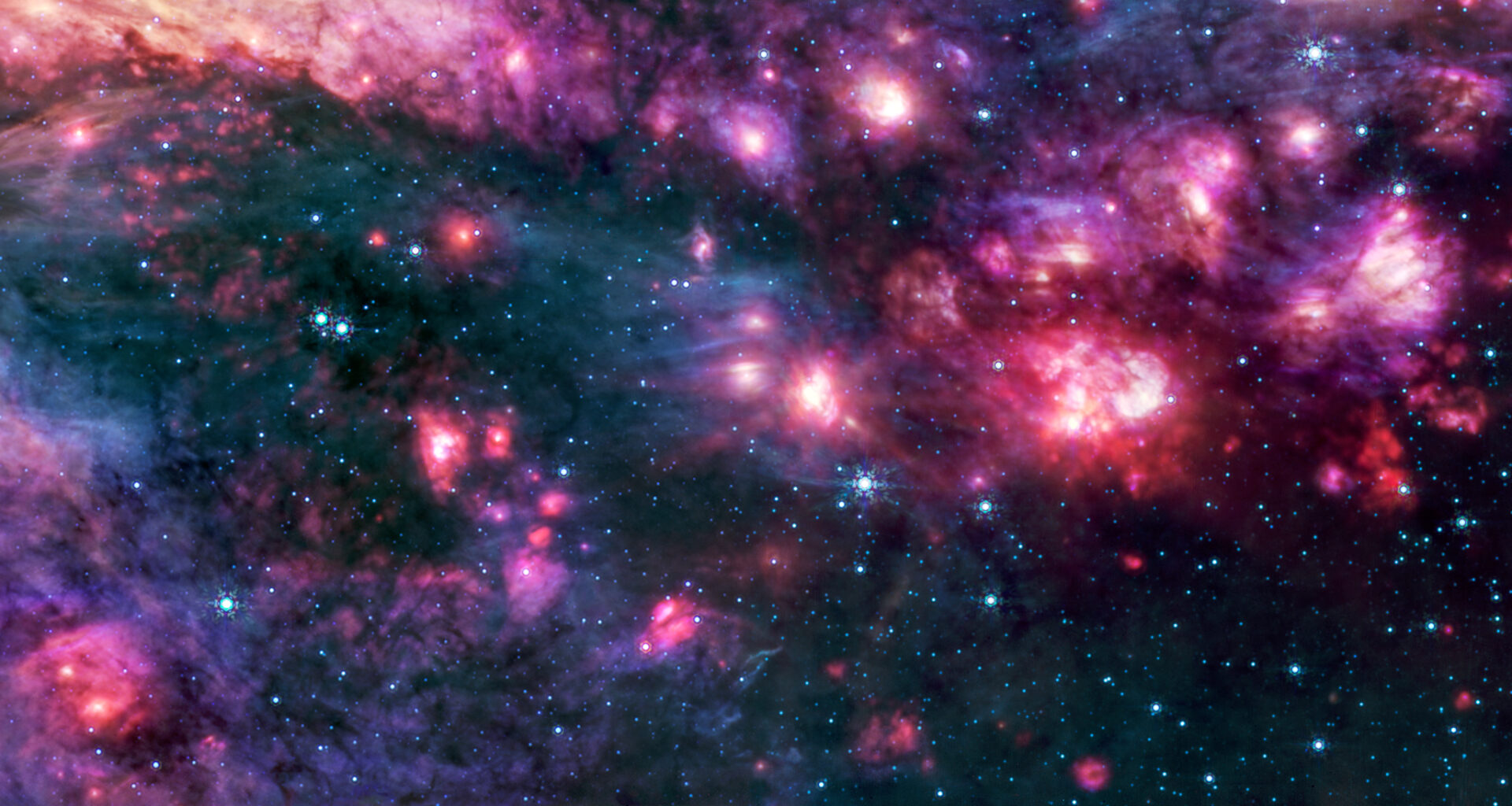 Cosmic clouds of pink and purple, some with bright centers, are surrounded by dark areas that appear like black space dotted with bright blue stars. A group of small clouds to the right is more red than any other area of the image.