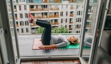 woman on her back side on to the camera with legs bent in the air. she's on a high rise balcony with blocks of flats behind her.