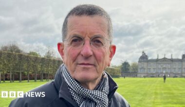 Sir Antony Gormley has short greyish black hair and is wearing rounded glasses.