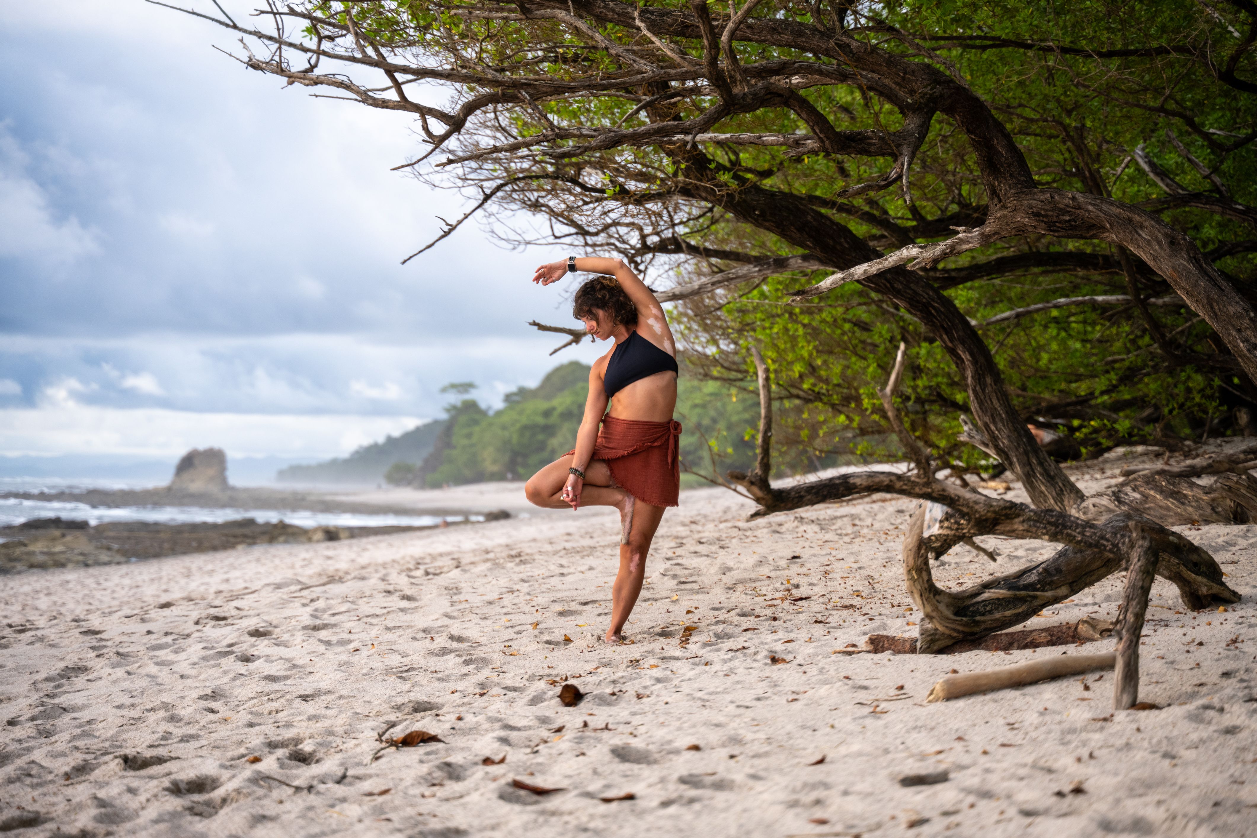 woman on beach doing standing yoga
