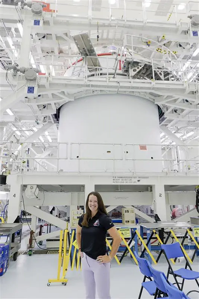 Branelle Rodriguez stands in front of Orion spacecraft. 