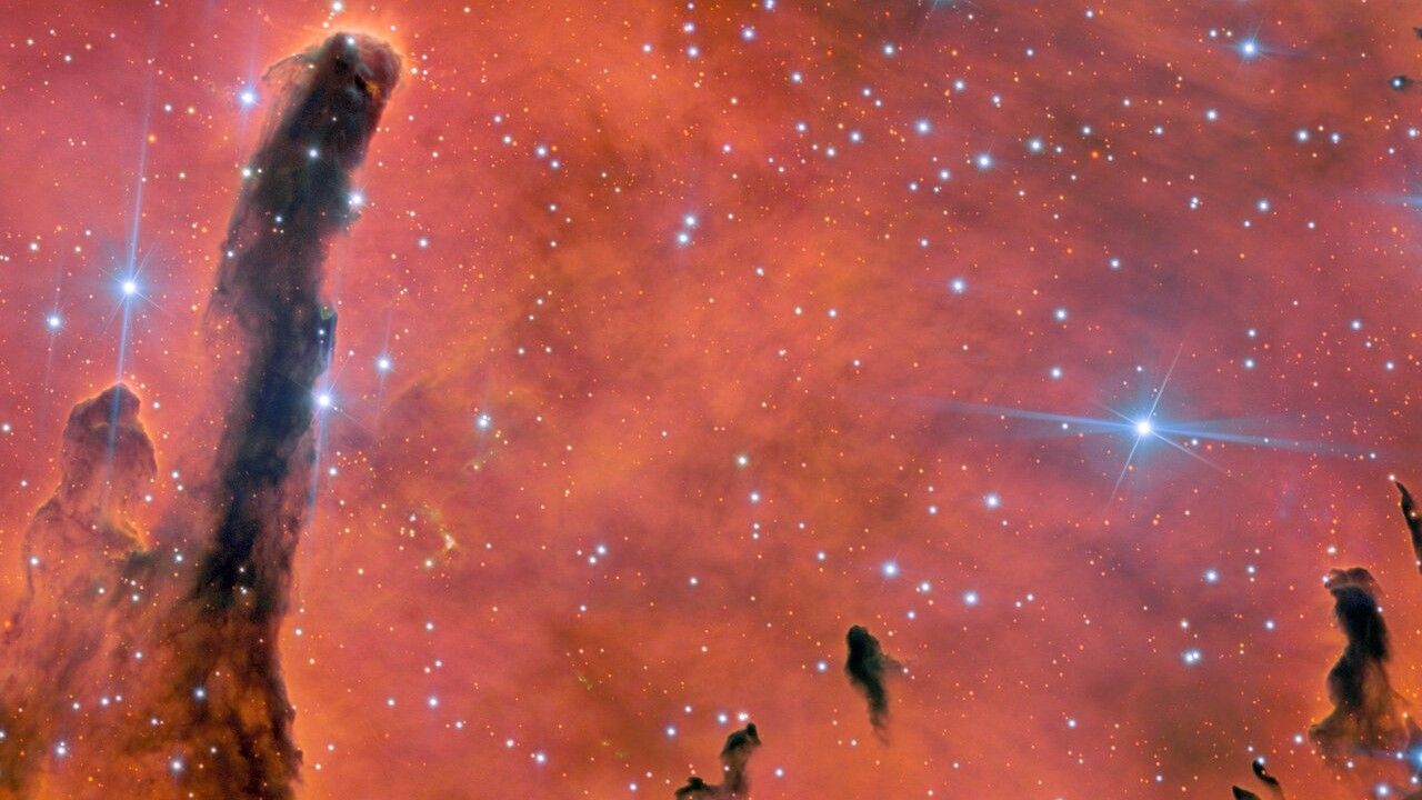 pillars of gas and dust against a fiery pink and orange background