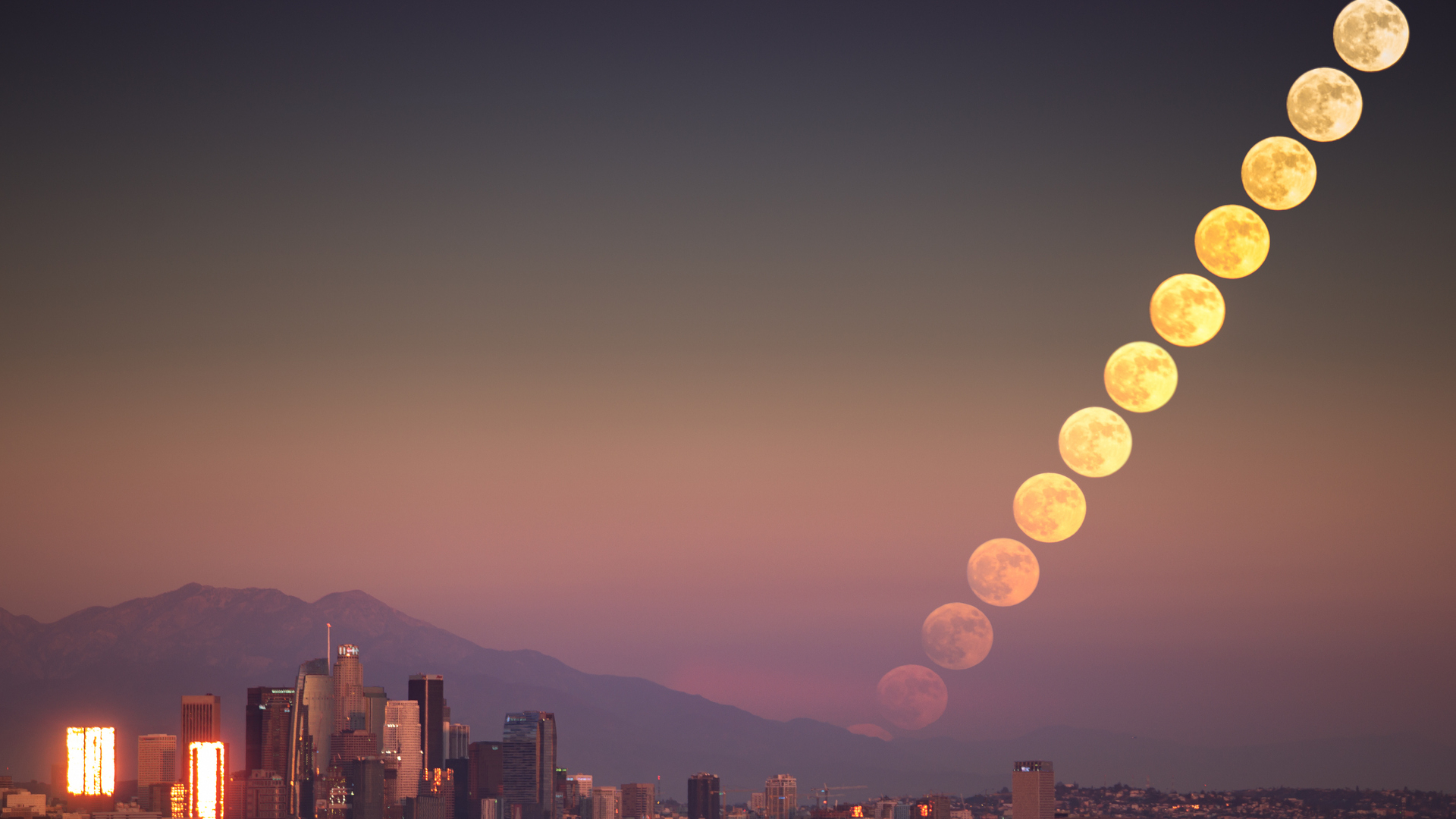 A composite image of a series of full moons shown moving diagonally across the cityscape's night sky, from bottom left to top right of the image