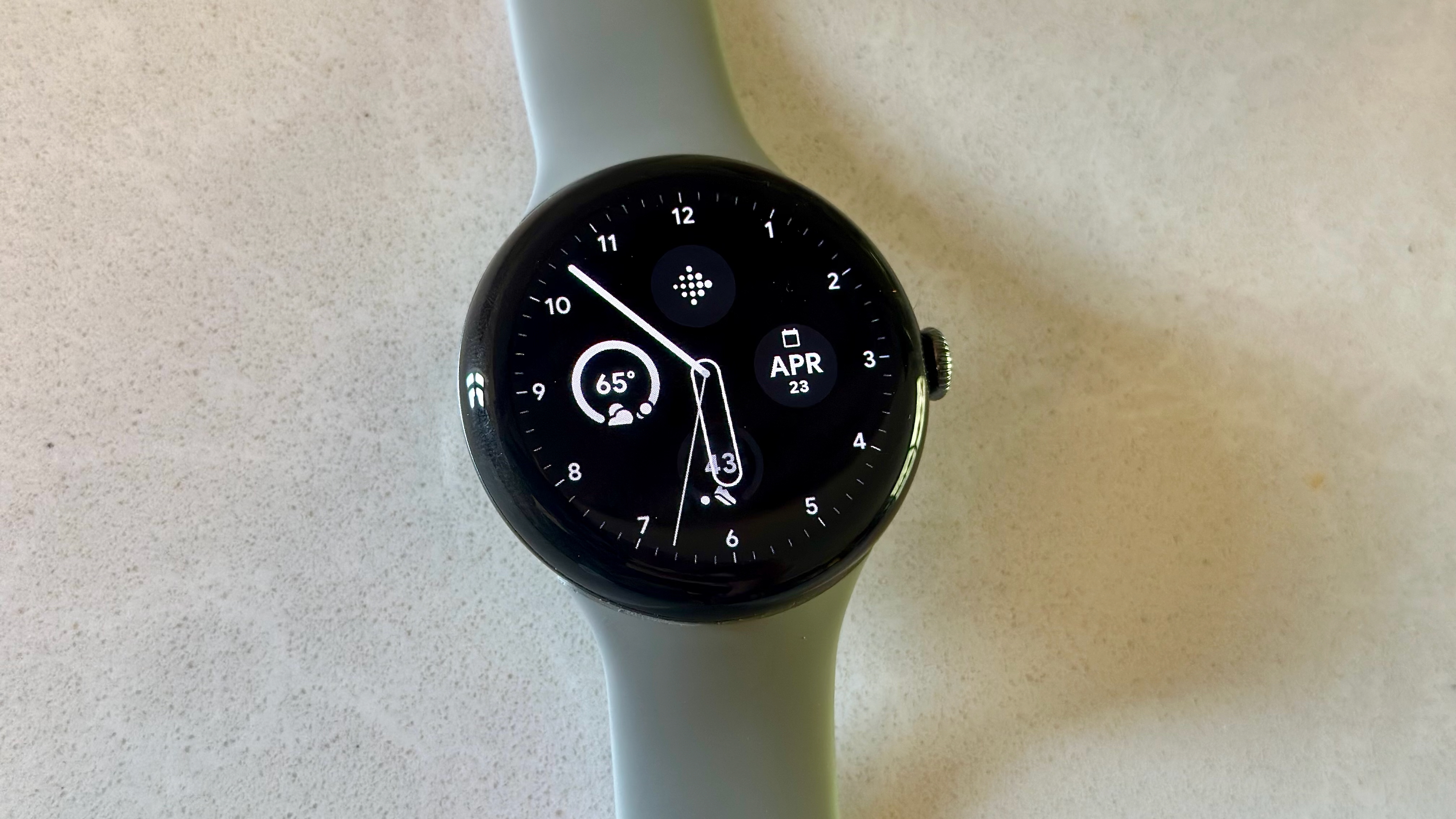 The Google Pixel Watch 3 on a white counter, showing the Pilot watch face.
