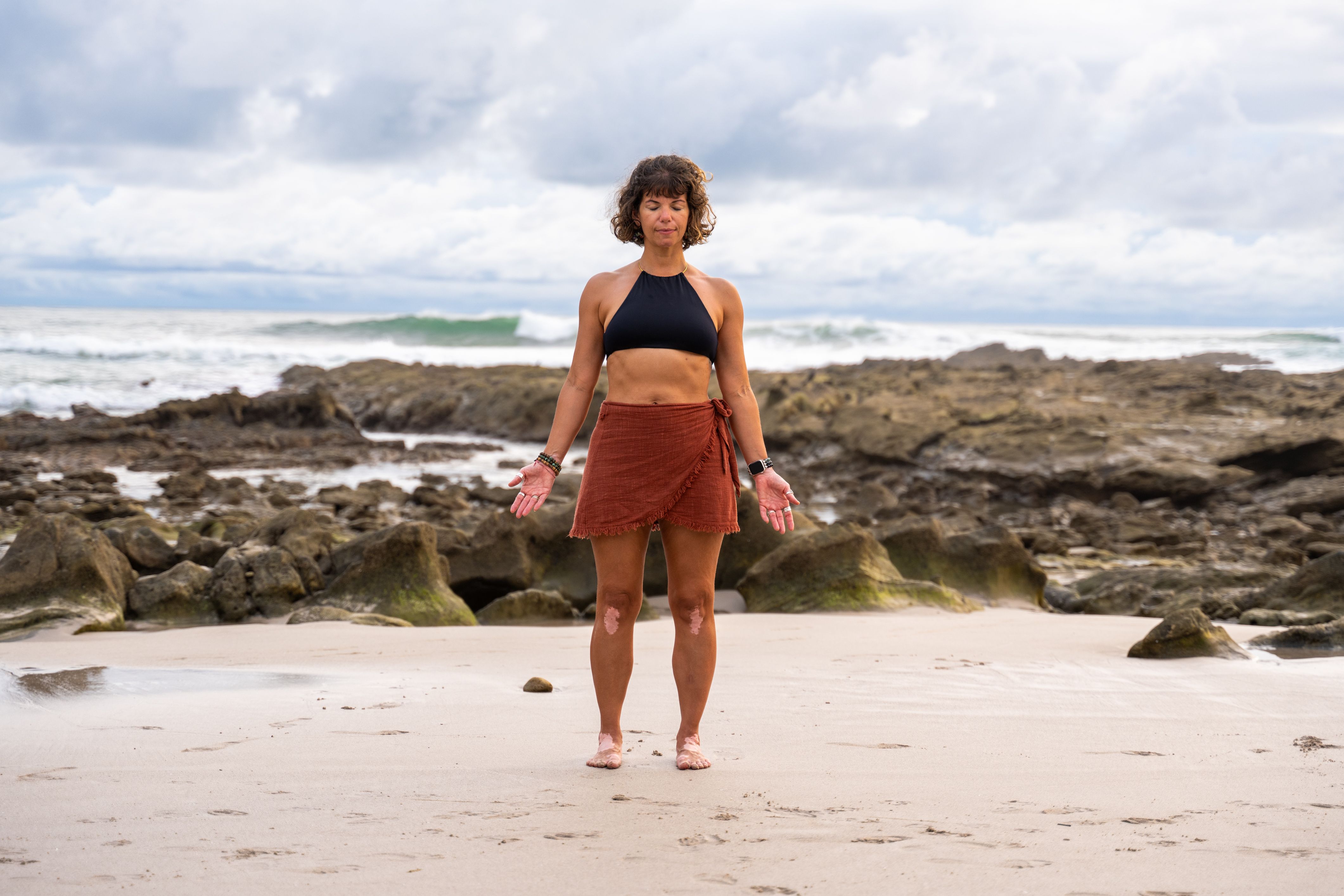 woman on beach doing standing yoga