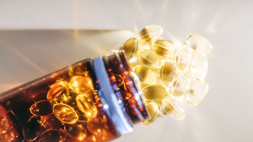 Supplements spill out of a container as the sunlight illuminates the gel capsules