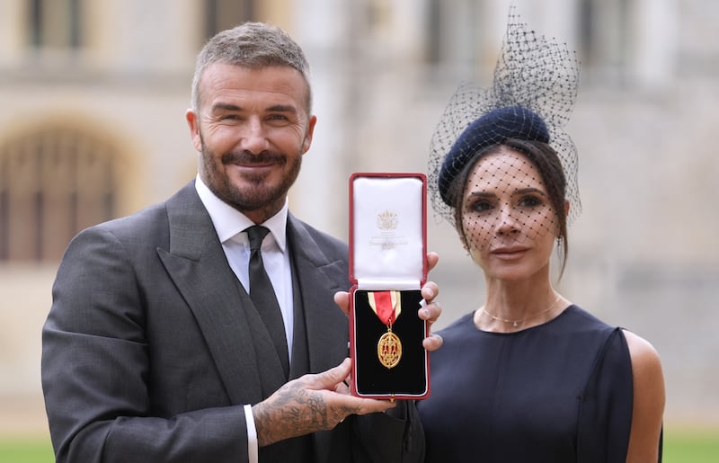 Sir David Beckham poses with his wife Lady Victoria after he was made a Knight Bachelor