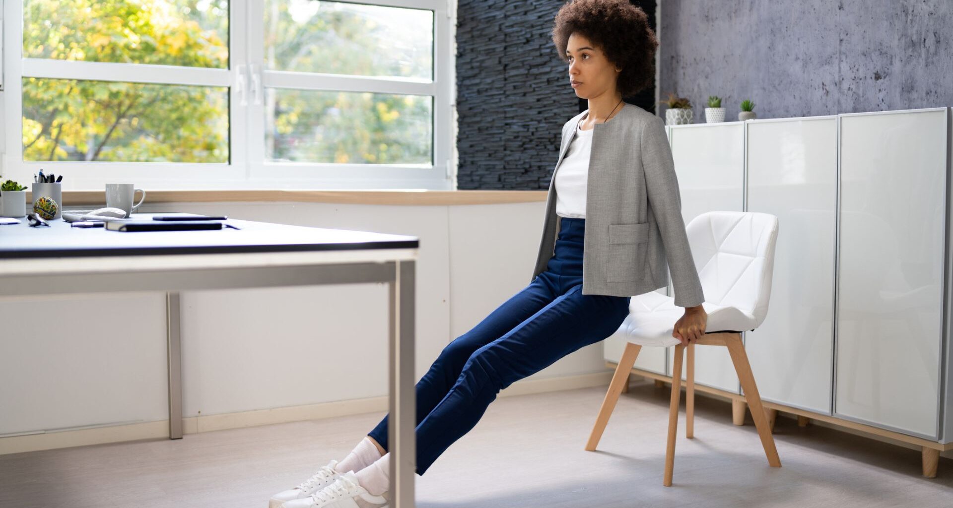 woman in work attire does tricep dips at her desk
