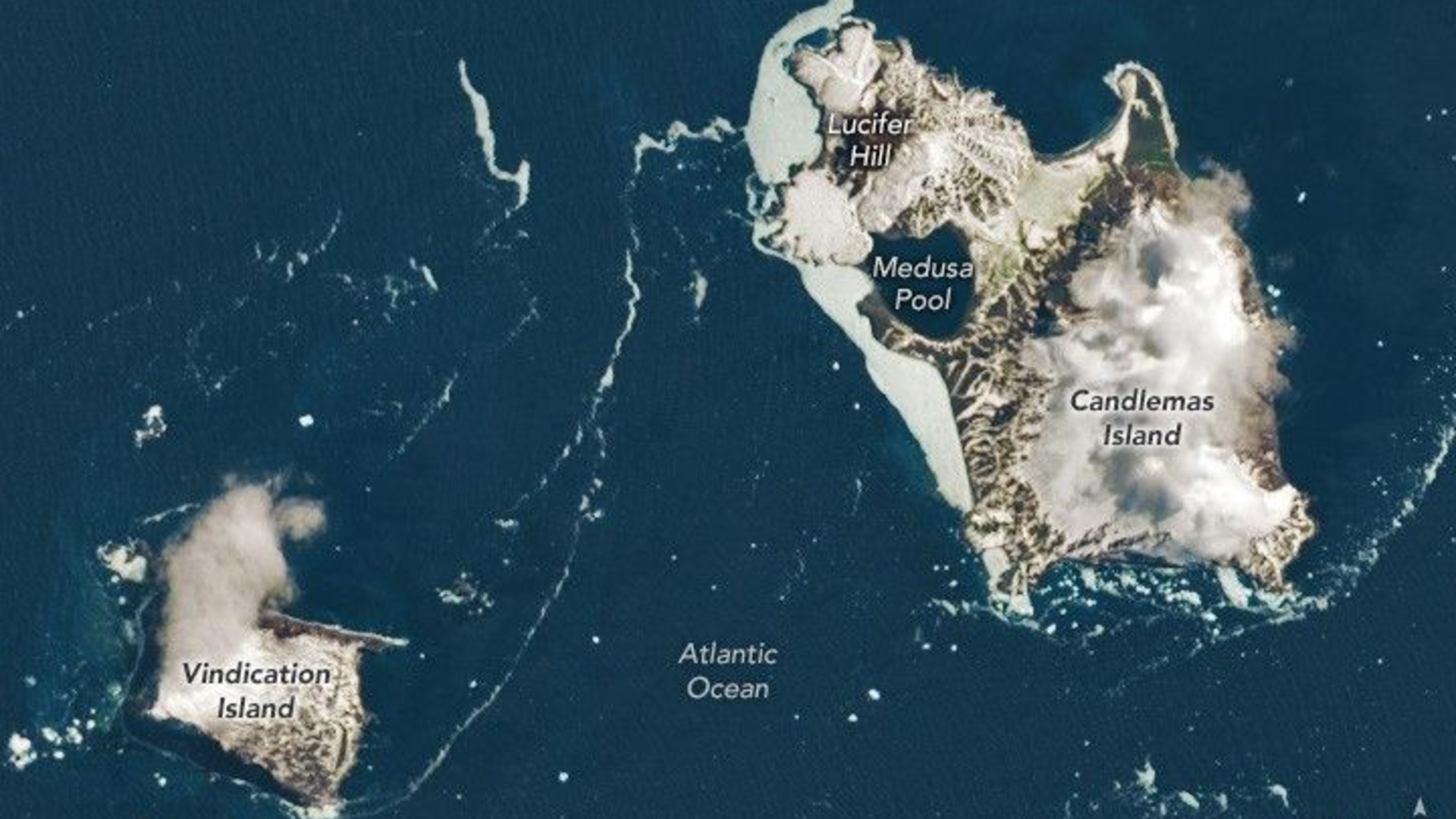 Two large brown and white islands are seen in a dark blue ocean from space with various labels including Vindication Island, Medusa Pool and Lucifer Hill