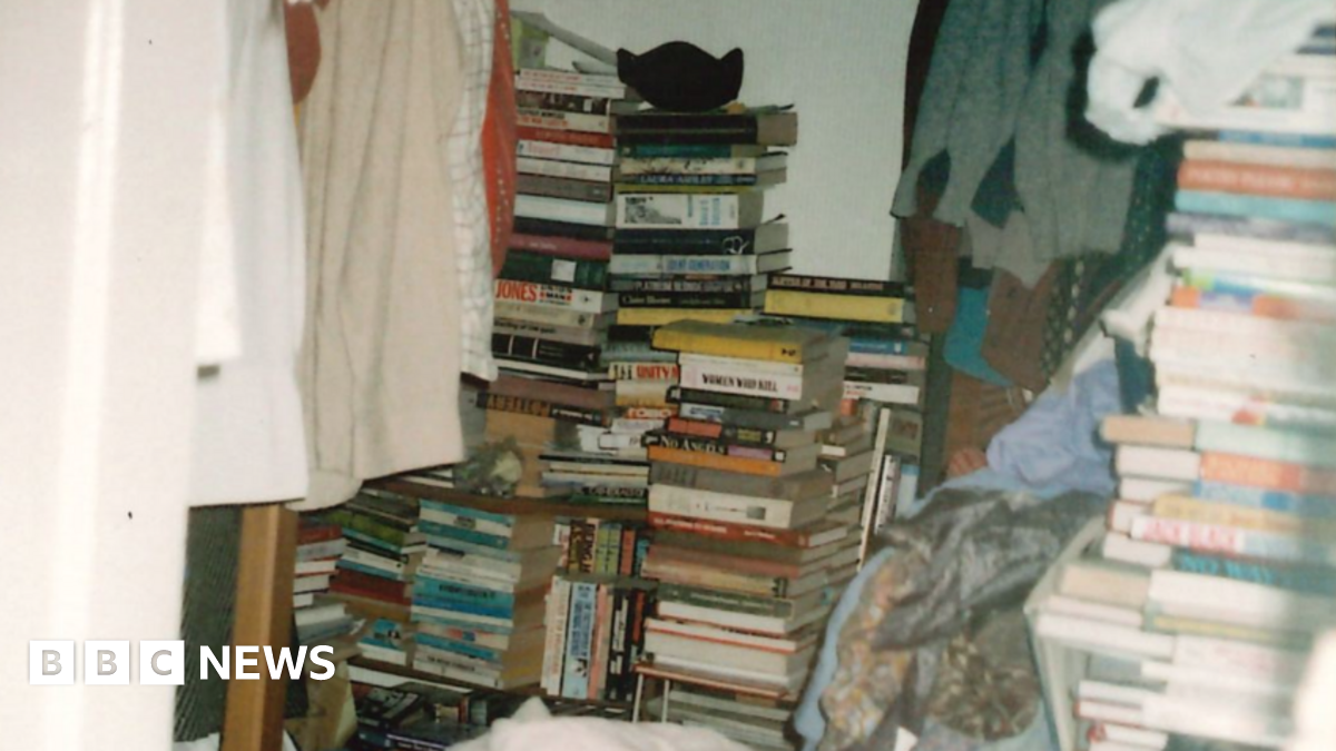 The bedroom of a person with hoarding disorder, stacked high with piles of books and clothes.