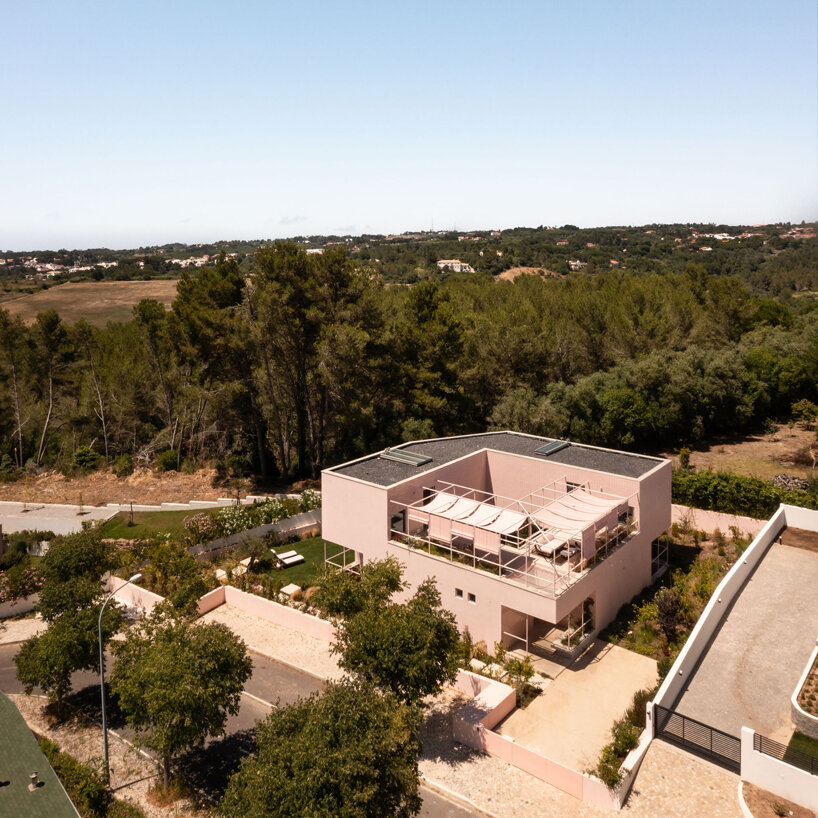 atelier RUA's light pink house contrasts with surrounding greenery in portugal