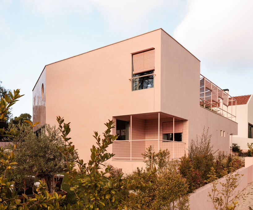 atelier RUA's light pink house contrasts with surrounding greenery in portugal