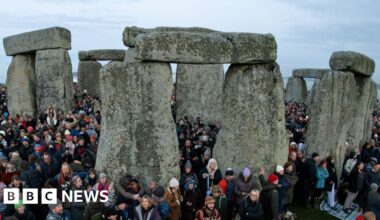 People stand at Stonehenge just after sunrise