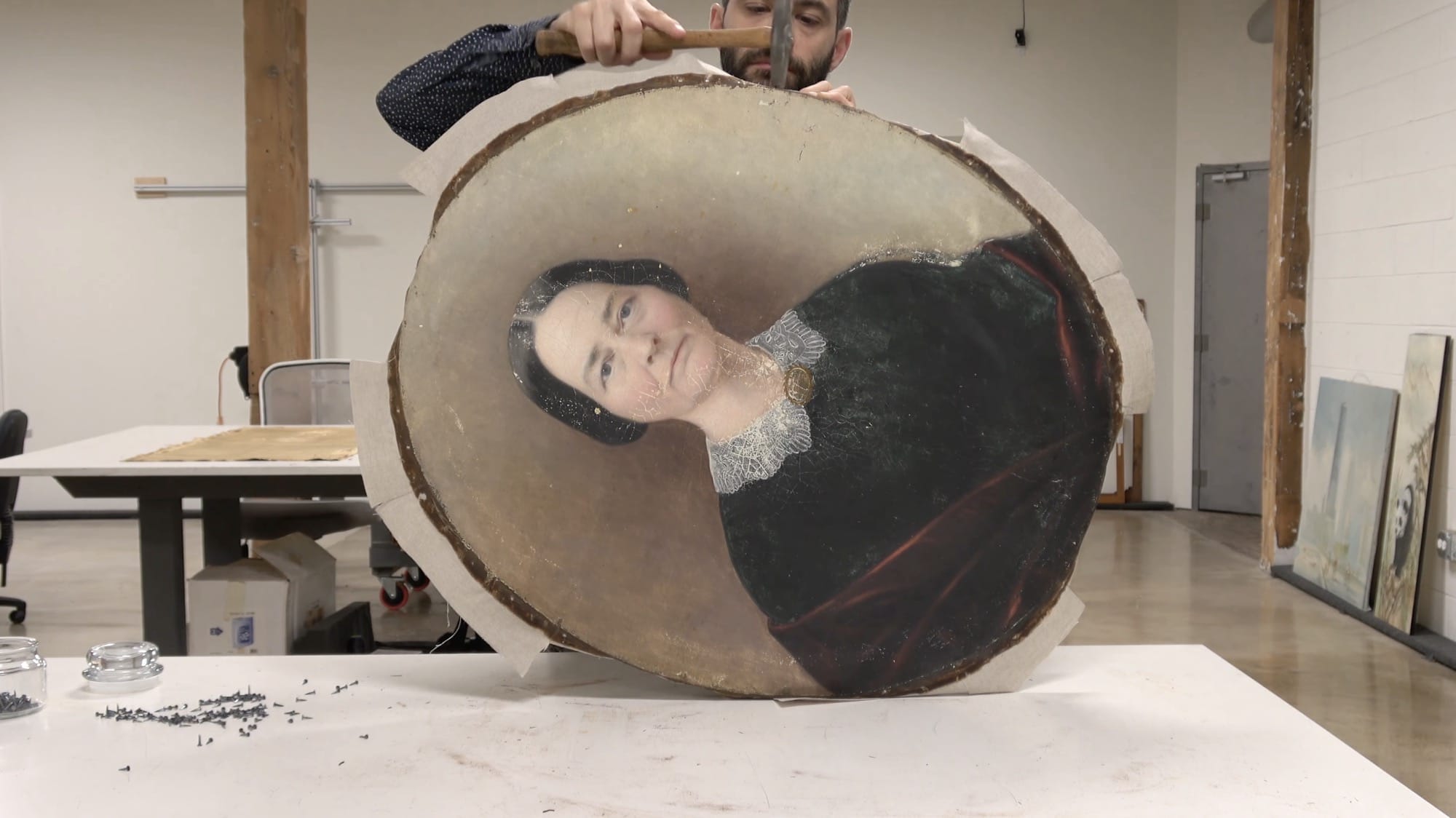 A still from a video of an oval portrait of a woman being restored