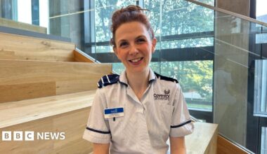 A woman with brown hair wearing a nurses uniform smiling.