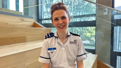 Hope Jezzard A woman with brown hair wearing a nurses uniform smiling. 