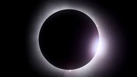 Getty Images The Moon passes in front of the Sun during a solar eclipse on April 08, 2024 in Martin Ohio. Millions of people have flocked to areas across North America that are in the "path of totality" in order to experience a total solar eclipse. During the event, the Moon will pass in between the Sun and the Earth, appearing to block the Sun. 
