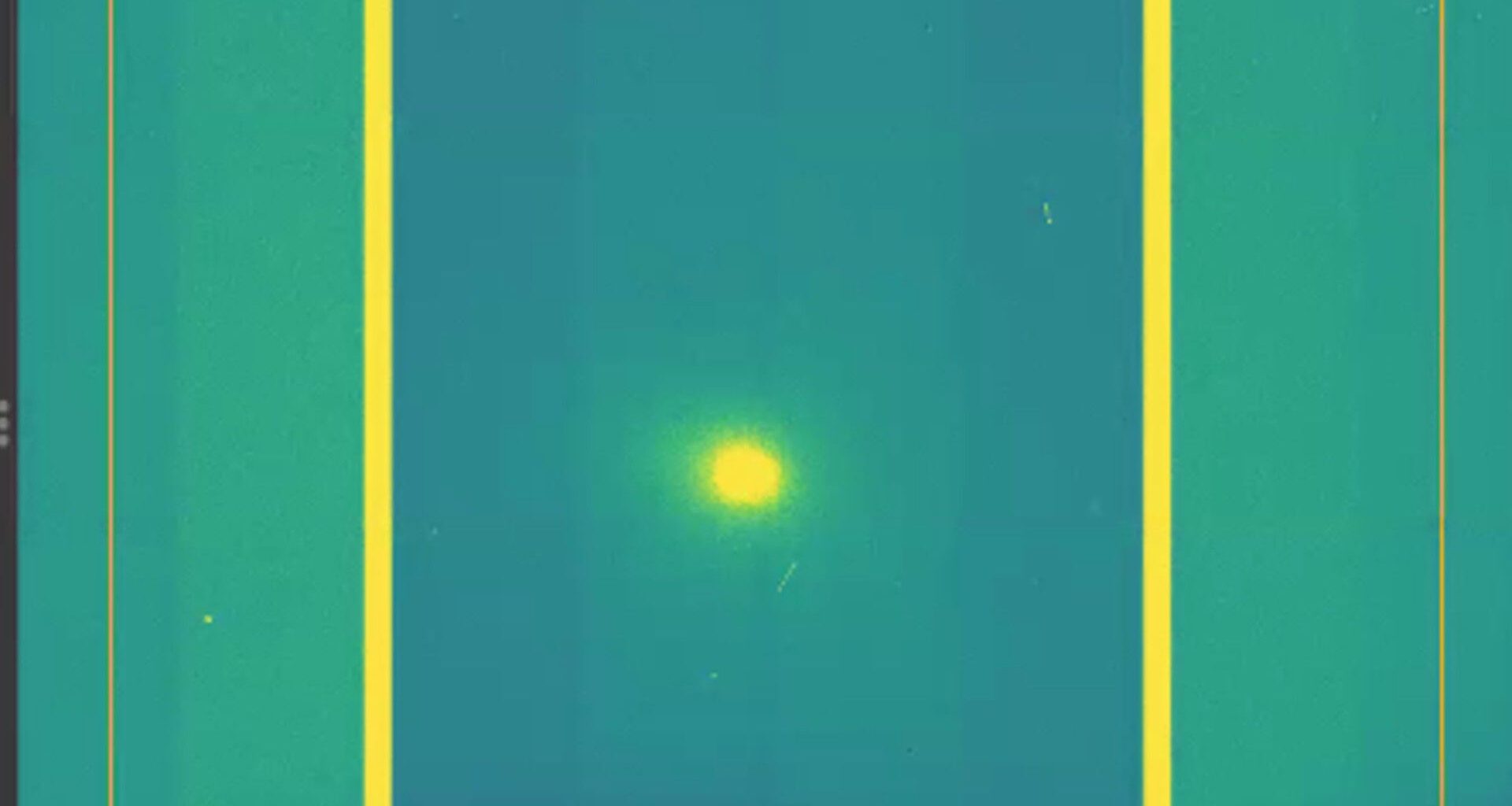 A screenshot of a yellow dot which is comet 3I/ATLAS in the middle of a green and purple background