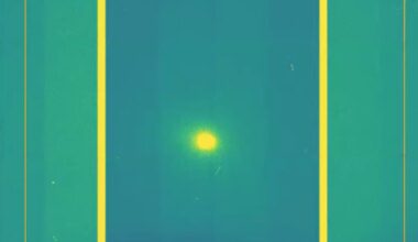 A screenshot of a yellow dot which is comet 3I/ATLAS in the middle of a green and purple background