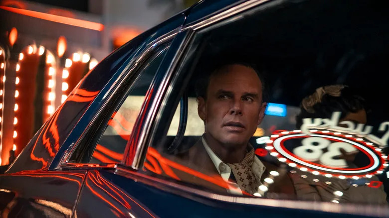 Cooper in a suit in a car driving through Vegas in Fallout