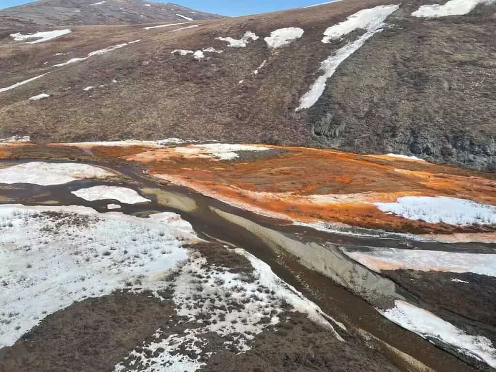 Iron causes orange water and snow in a braidplain of the Nakolikruk River, Alaska.