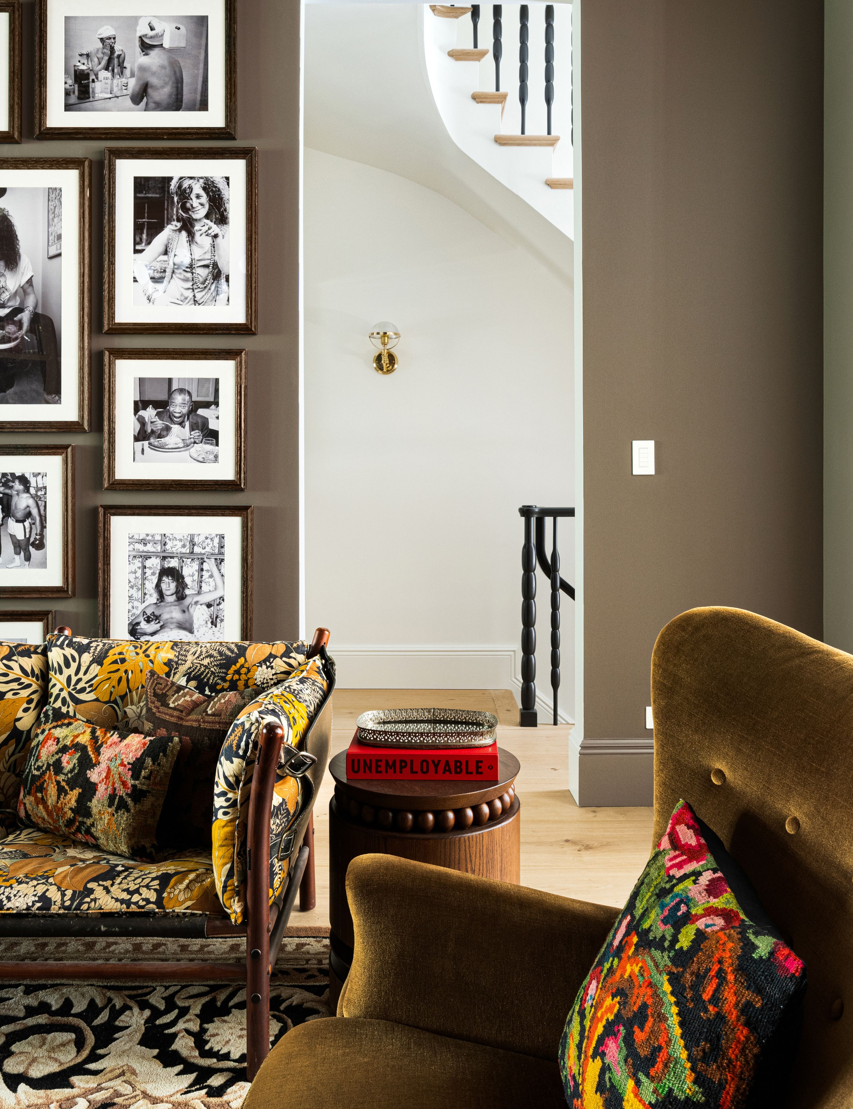 Pattern-filled NYC parlor room featuring a floral sofa, green velvet accent chair, and stacks of colorful coffee table books