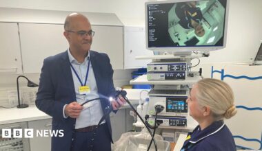 Dr Sanjeev Pattni, a consultant Gastroenterologist and co-head of service at Leicestershire's Hospitals, showing a nurse the endoscopy equipment in a medical room.