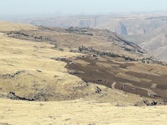 A barren brown mountainous landscape with a few tiny buildings dotted around