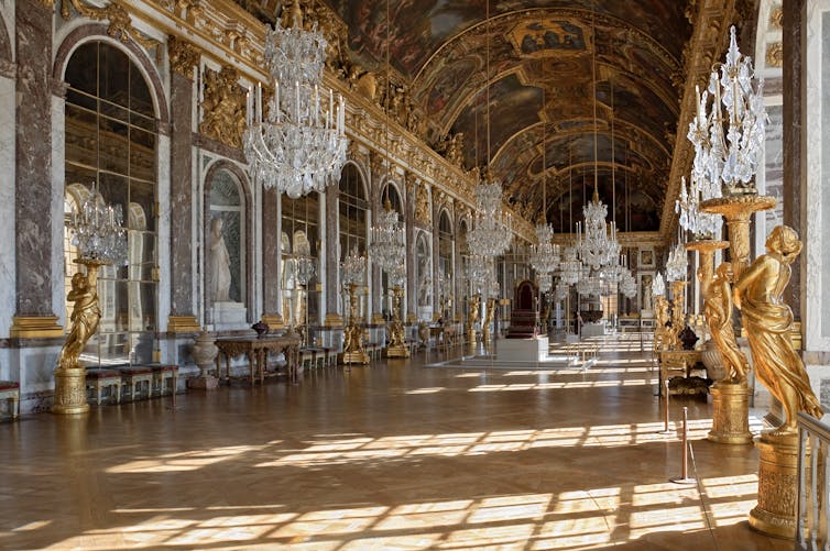 An opulent hall with mirrors on each wall, crystal chandeliers and ornate gold detailing
