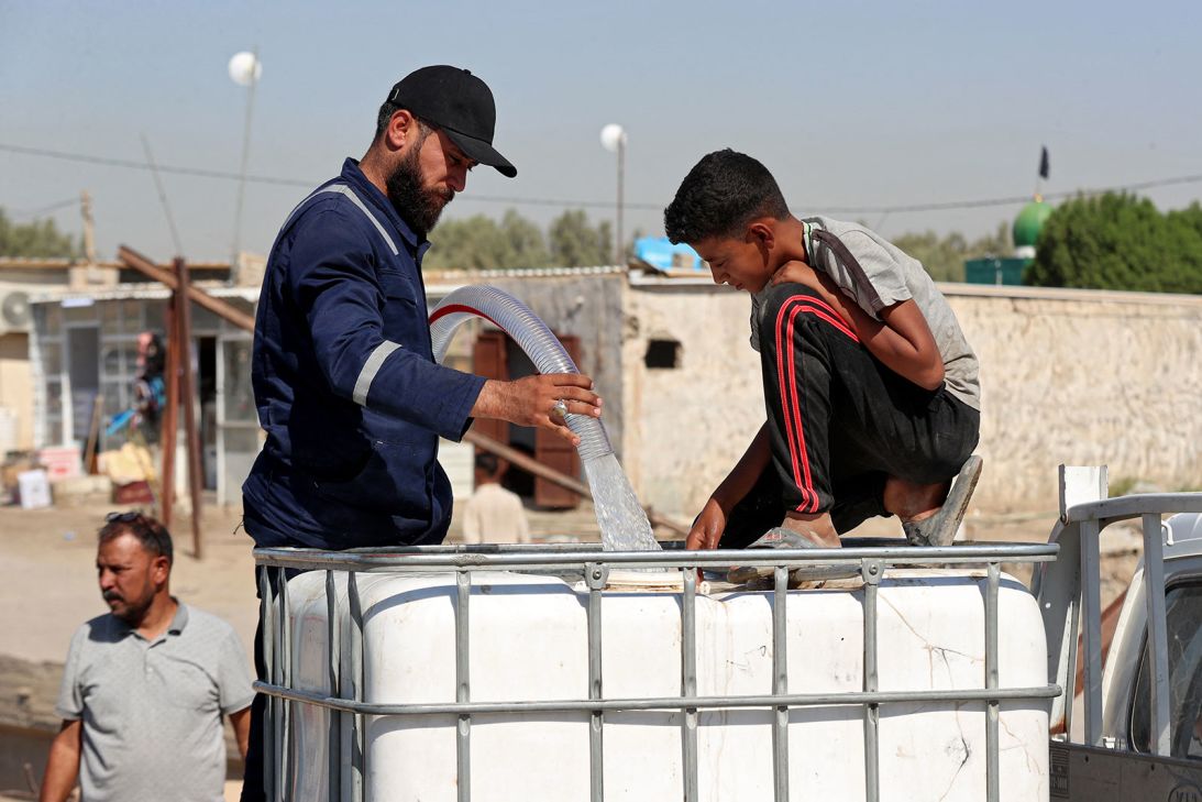 Residents of drought-affected villages fill their water containers at a distribution point in the town of al-Khudariyah, in Iraq's central Babel province, on September 15, 2025.